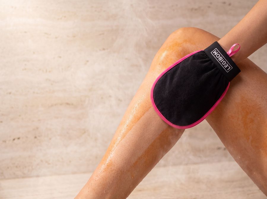 Legibom mitt removing patchy self-tan from a leg